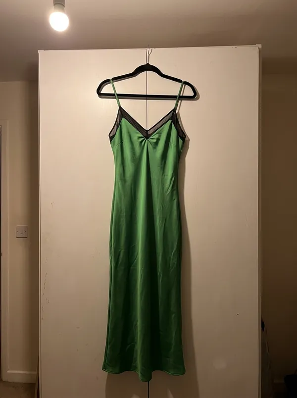 green satin midi dress on a hanger over a wardrobe door