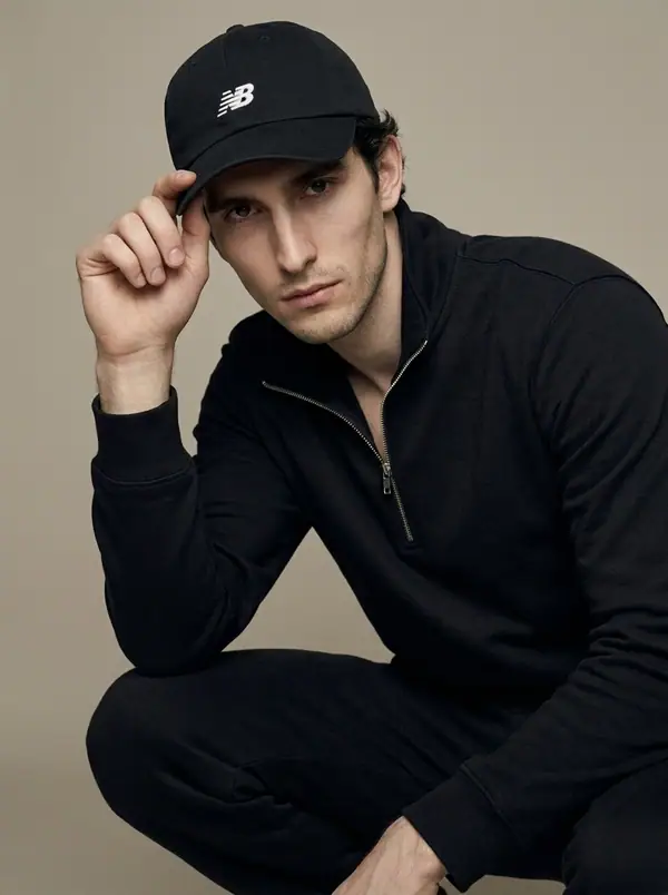 black NB cap hero + quarter-zip funnel sweat worn by an AI male model, studio shoot
