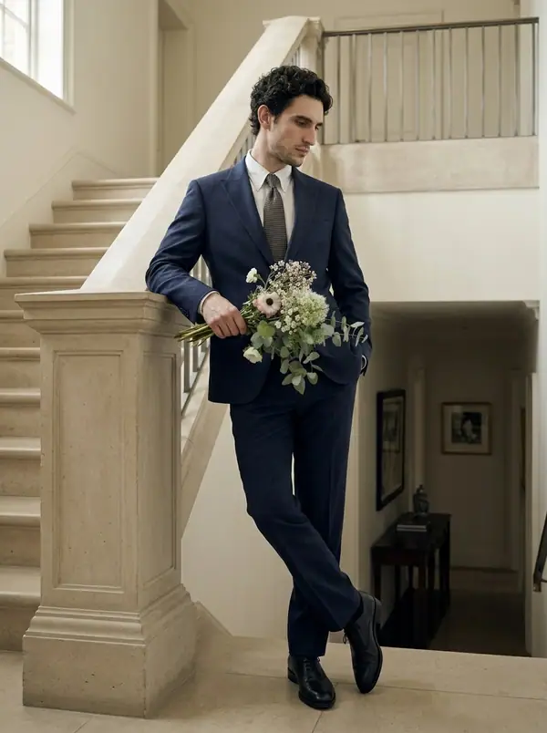 navy double-breasted linen suit + embroidered cap worn by an AI male model, editorial shoot