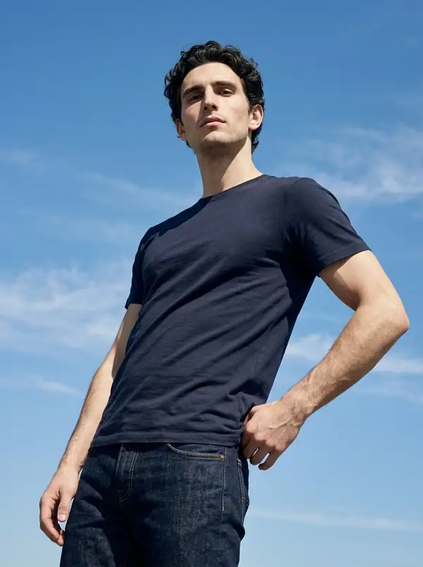 navy midweight crew tee, sky hero angle worn by an AI male model, editorial shoot at against the sky